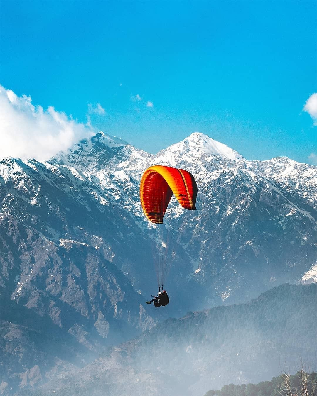 aragliding adventure in Solang Valley with snowy mountains in the background.